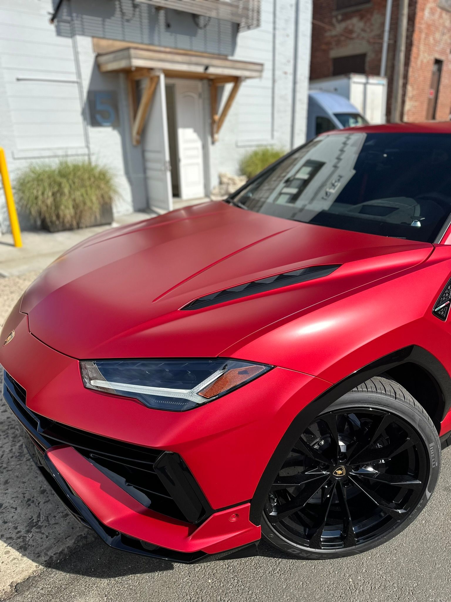 Red Lamborghini Urus with ceramic coating and PPF parked outside a dealership