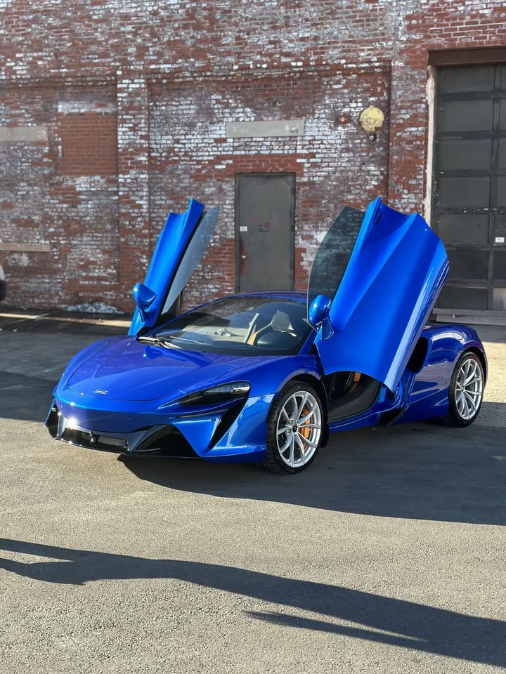 Blue McLaren Artura with a deep gloss ceramic-coated finish outside the Auto Customs shop